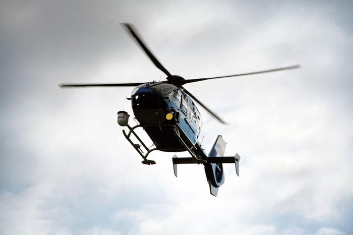 Blue and silver police helicopter flying above Wall Mural Wallpaper